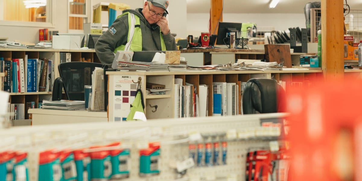 Interior view of a Western Building Center store showing an employee in a high-visibility safety vest working at a counter ar
