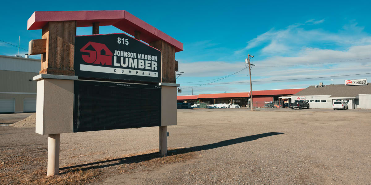 Exterior view of Johnson Madison Lumber Company facility at 815, showing a prominent business sign with red and black brandin