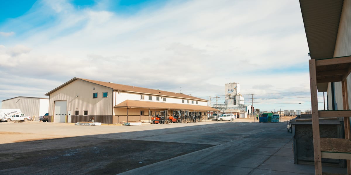 Industrial facility exterior showing concrete loading dock areas with metal warehouse buildings in the background