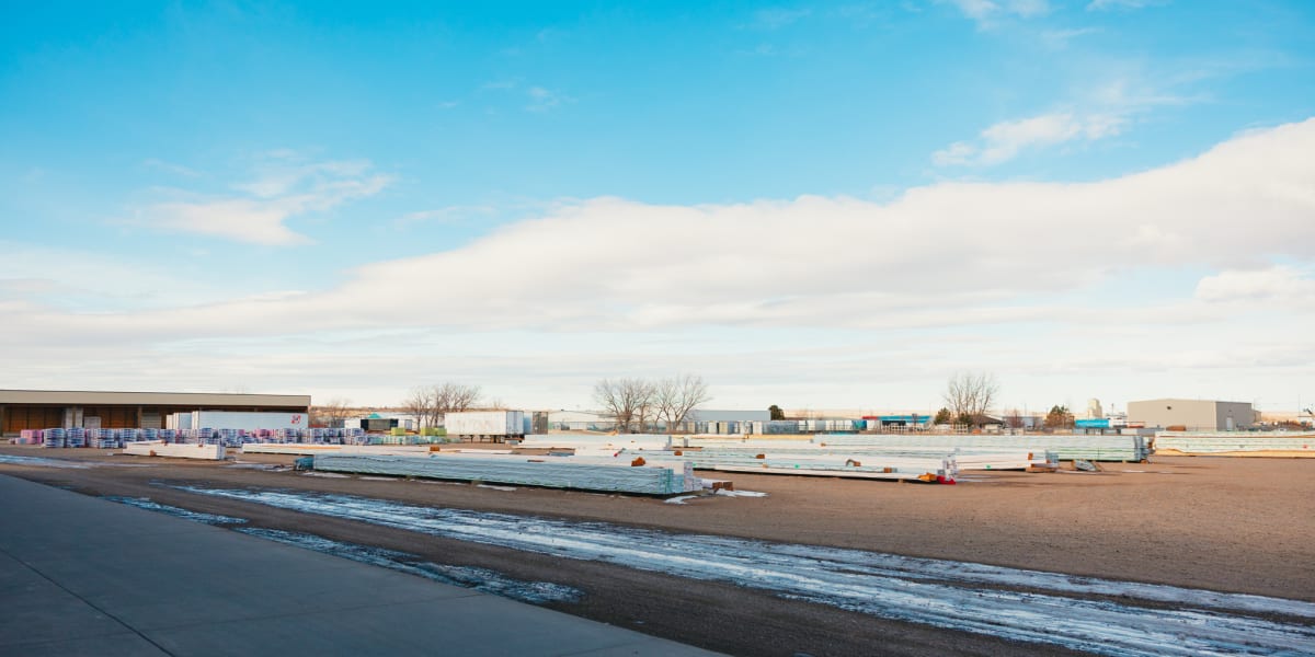 A wide view of a lumber yard and building supply facility on a winter day with patches of snow on the ground