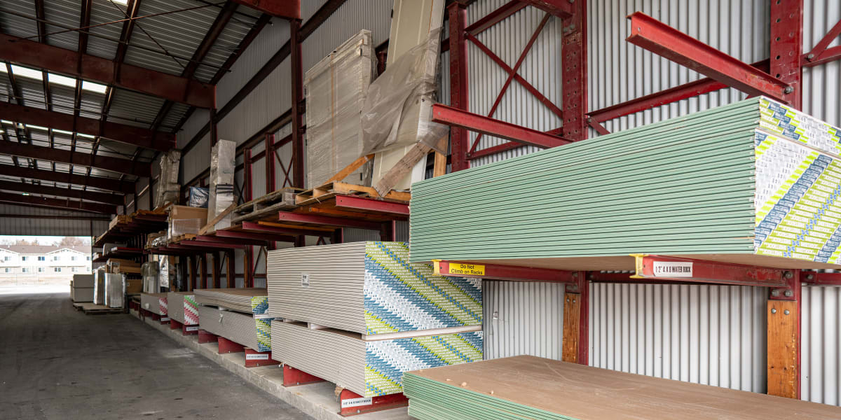 Interior view of a warehouse lumber storage area showing organized stacks of building materials on red cantilever racking sys