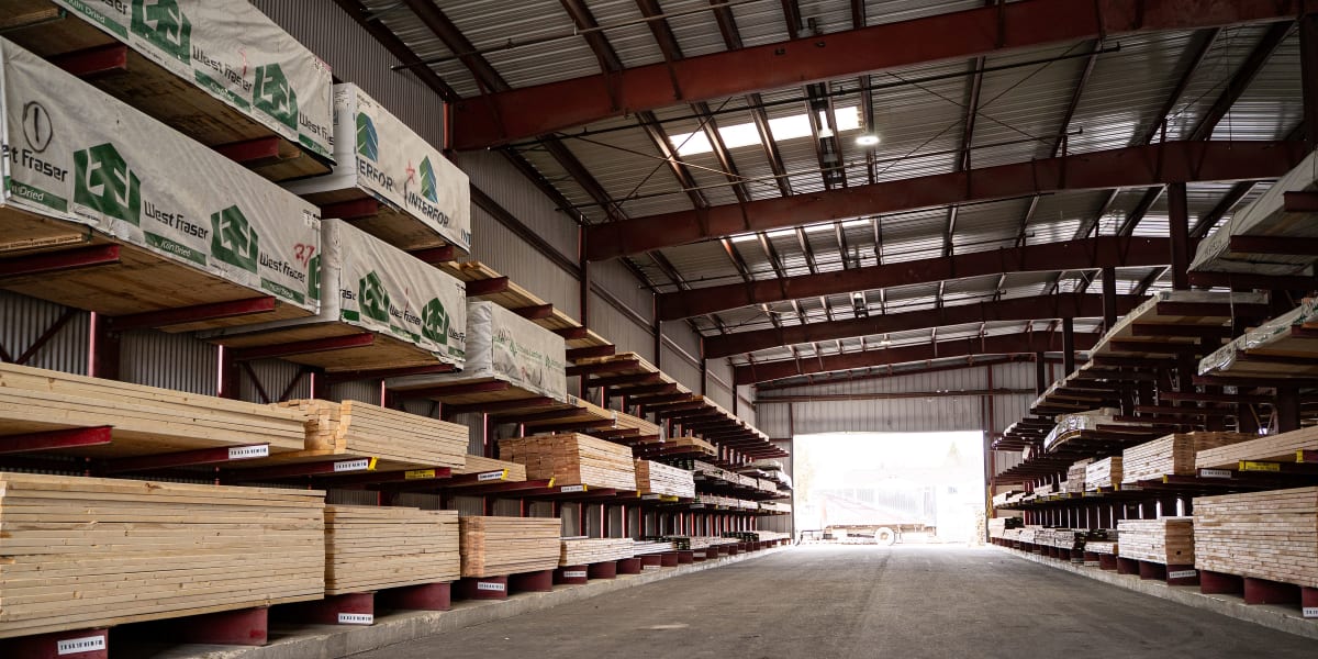 Interior view of a large lumber warehouse with extensive cantilever racking systems storing dimensional lumber and engineered