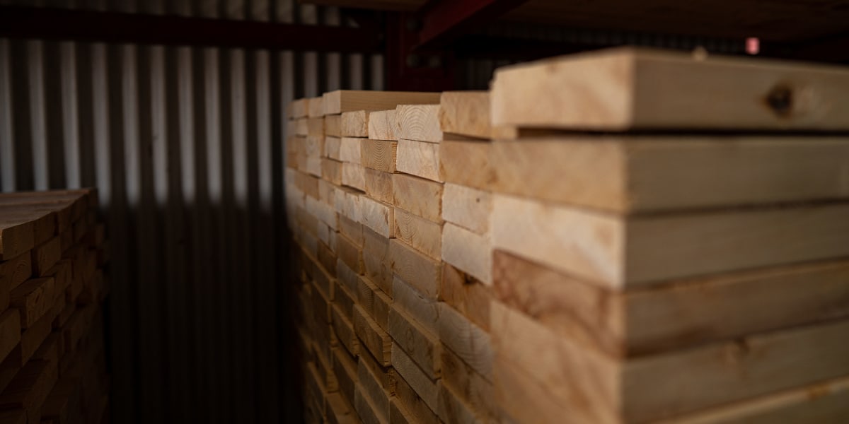 Interior view of a lumber warehouse storage area showing neatly stacked dimensional lumber organized on shelving systems