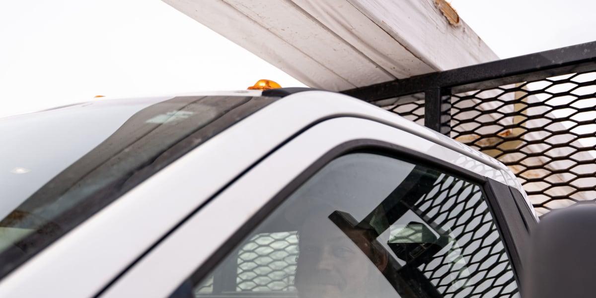 Interior view of a police or security vehicle showing an officer in bright orange safety clothing visible through the side wi
