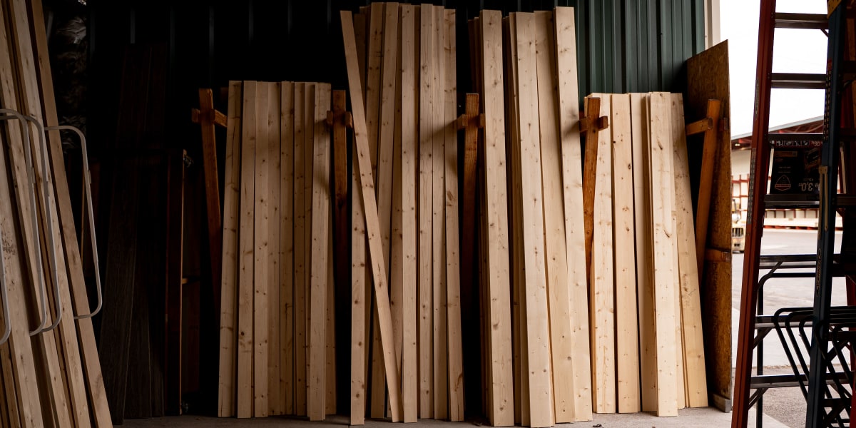 Interior view of a lumber storage warehouse showing organized stacks of dimensional lumber boards stored vertically in wooden