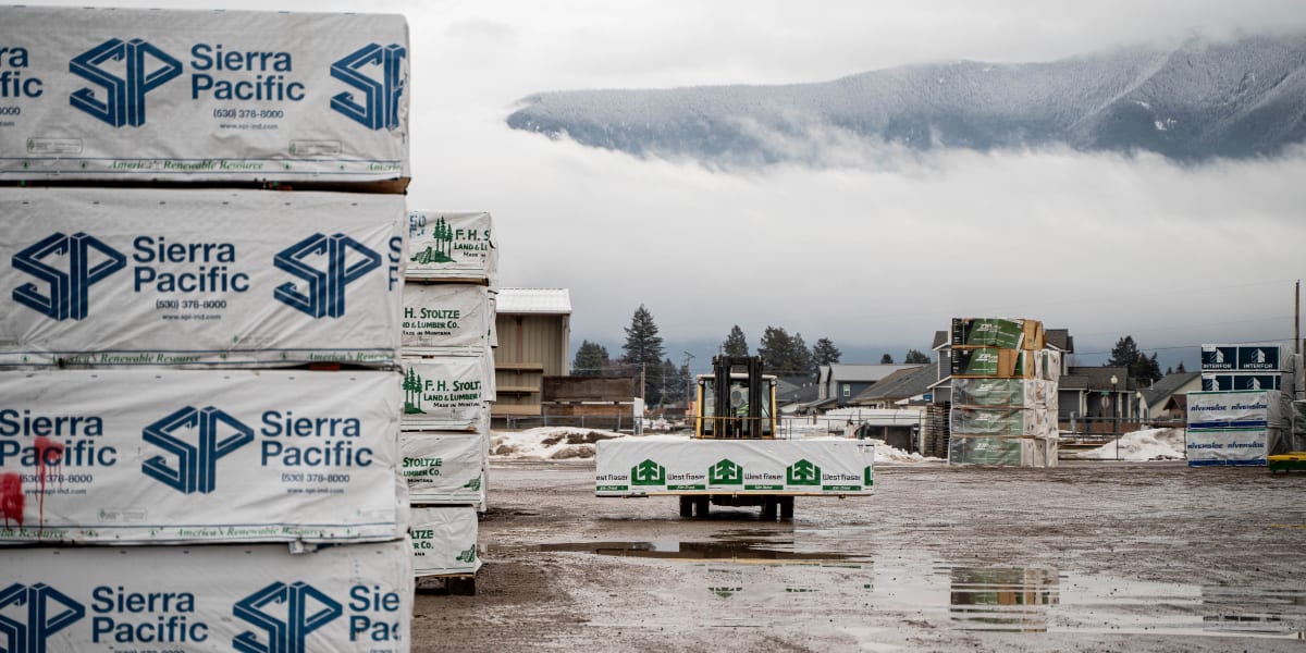 A lumber yard and building materials storage facility on a foggy day with mountains visible in the background
