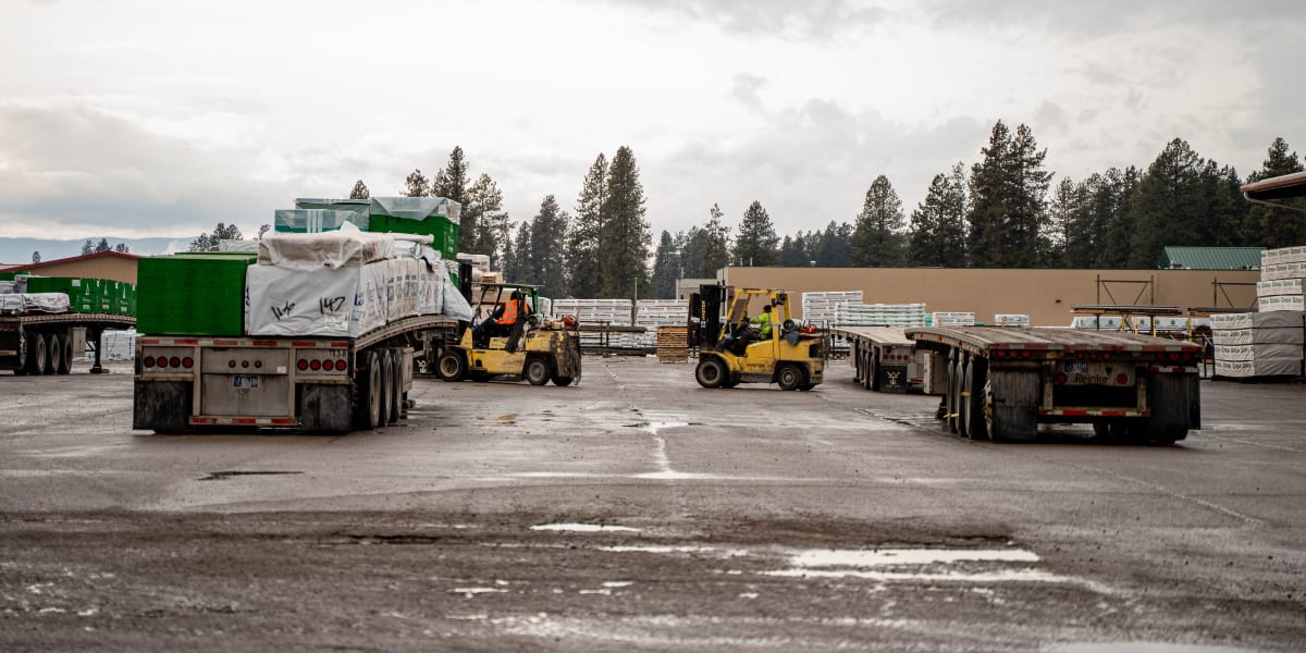 This image shows the Western Building Center corporate yard with multiple semi-truck trailers positioned for loading and unlo