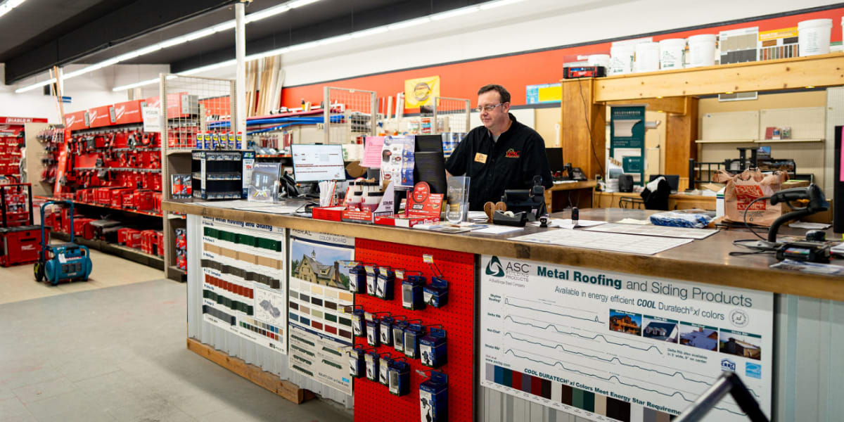 Interior view of the Western Building Center Libby store showing the customer service counter area with an employee working b