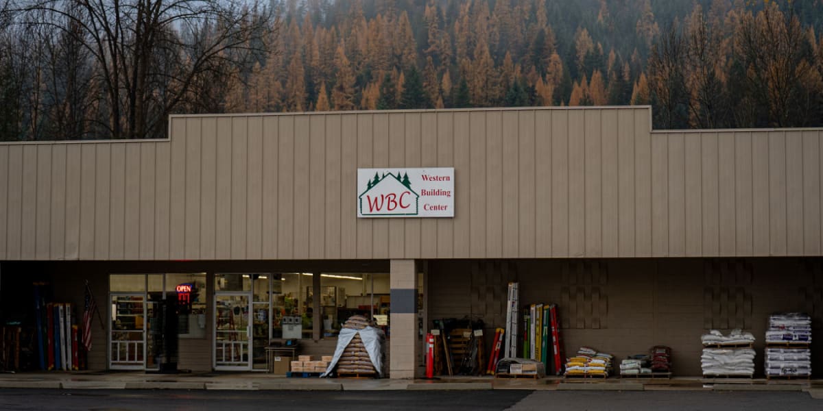 Exterior view of Western Building Center's Libby location showing a single-story commercial building with tan/beige metal sid