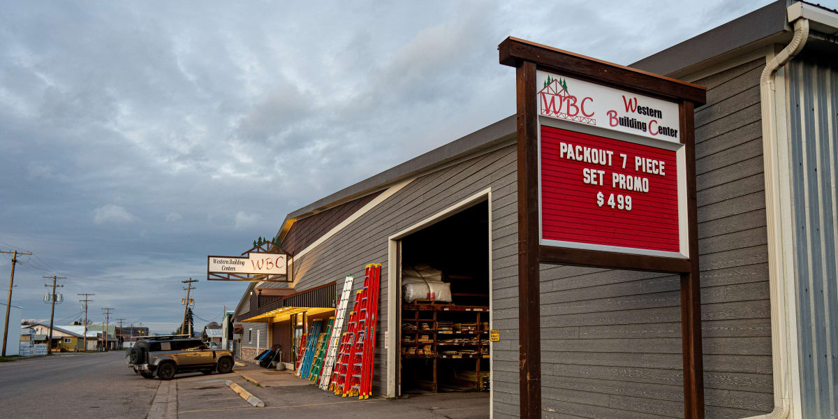 Exterior view of Western Building Center's Polson location showing the main storefront with gray metal siding and an open gar