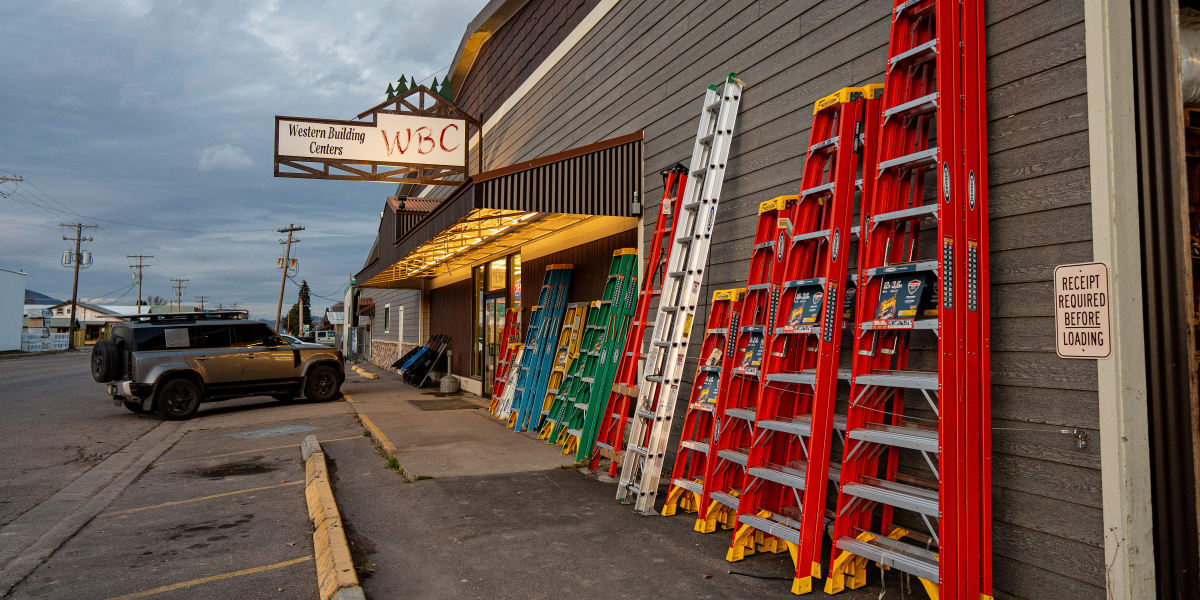 Exterior view of Western Building Centers store showing a large display of colorful fiberglass step ladders lined up against