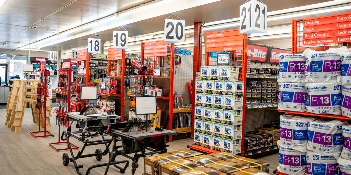 Interior view of a Western Building Center store showing multiple aisles with overhead aisle number signs (18, 19, 20, 21, 21