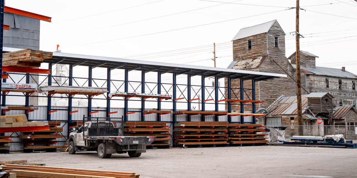 This image shows the lumber yard area of a Western Building Center store with a large metal storage structure for lumber and