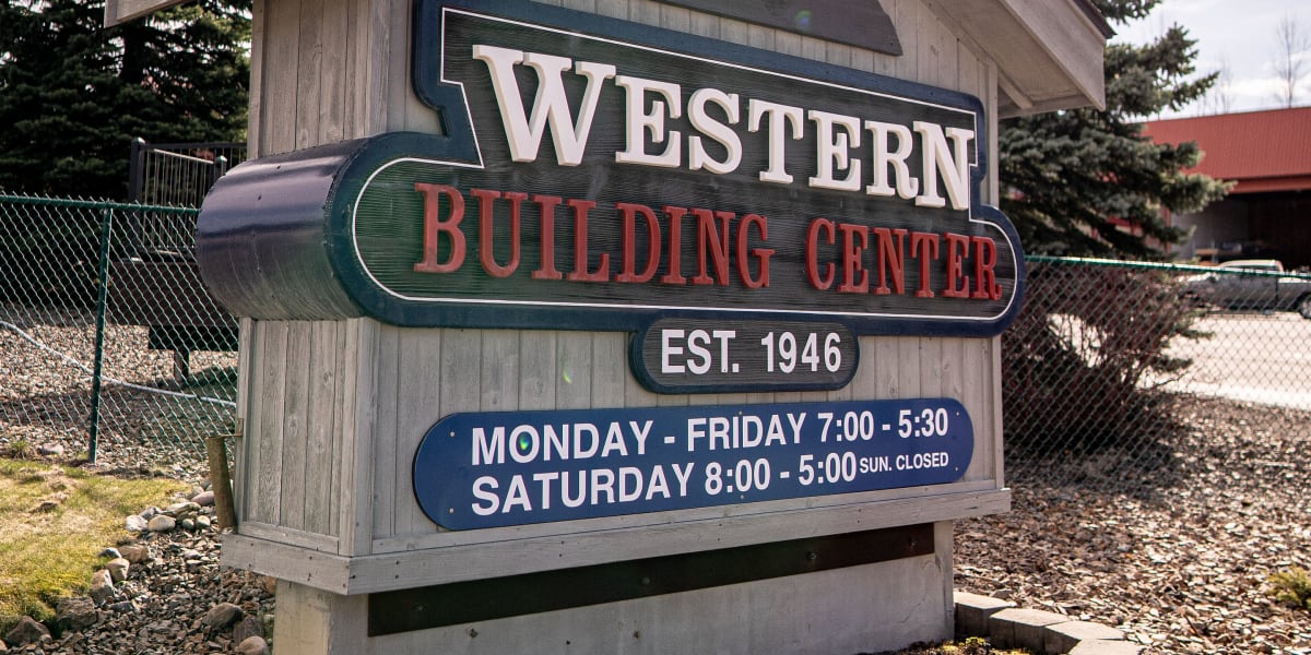 A wooden entrance sign for Western Building Center displaying the company name, establishment date of 1946, and business hour