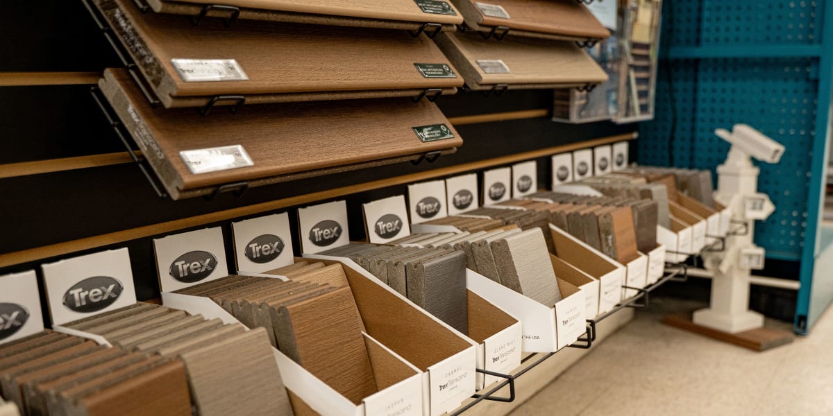 Interior store display showing Trex composite decking samples organized in white boxes with metal wire stands