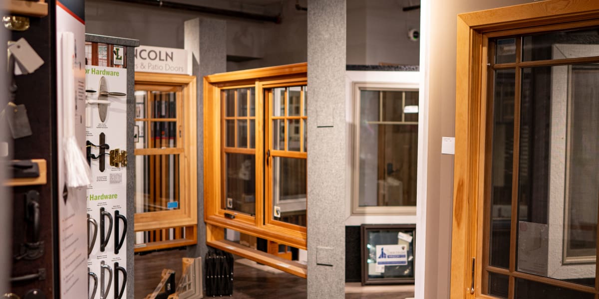 Interior view of a showroom displaying various window and door products with wood frames and trim