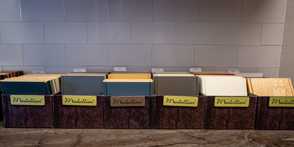 This image shows an organized display of various door and millwork samples arranged in dark wooden storage boxes with yellow