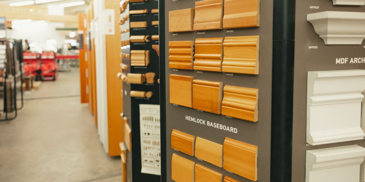 Interior view of a building supply store's millwork department showing a display wall of wood trim and molding samples