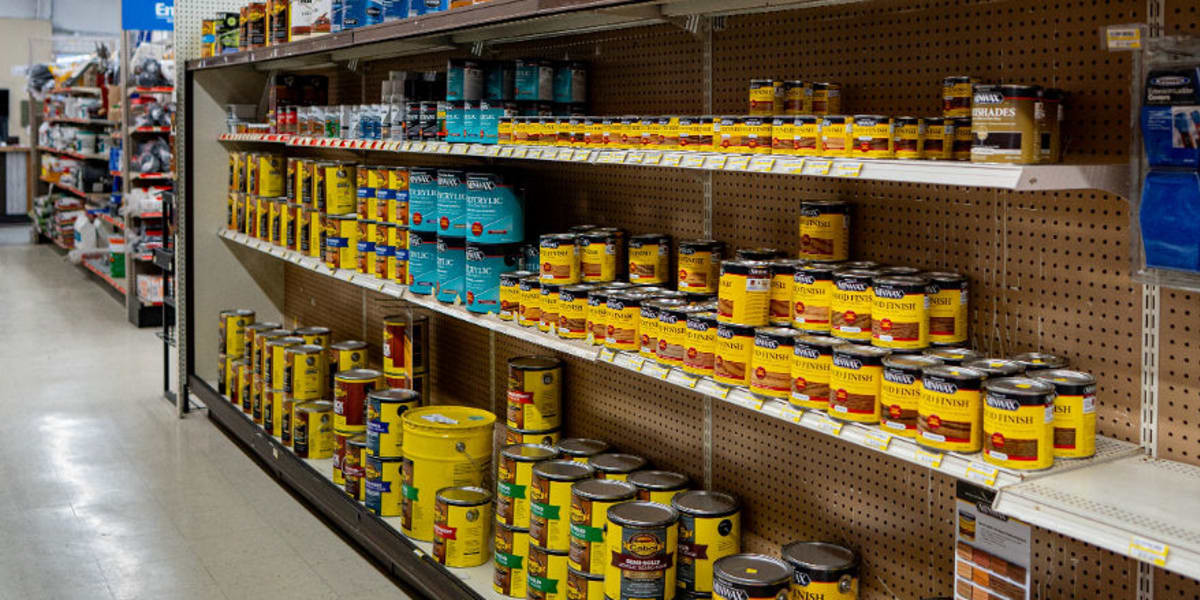 Interior view of a paint department aisle showing multiple shelves stocked with wood stains and finishes