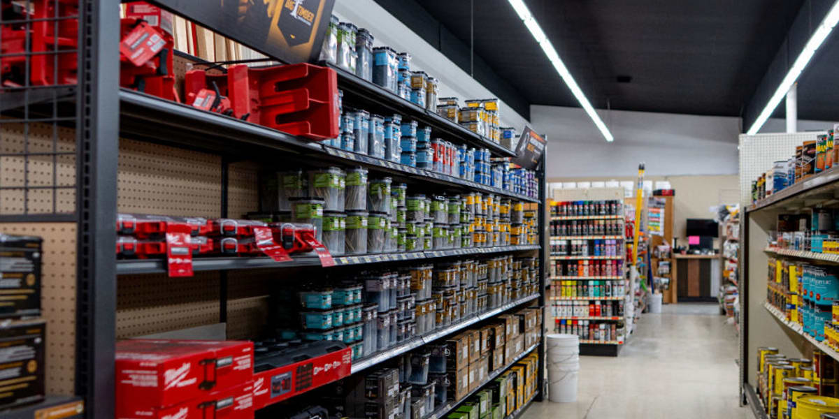 Interior view of the paint department showing multiple shelves stocked with paint cans, stains, and wood finishes