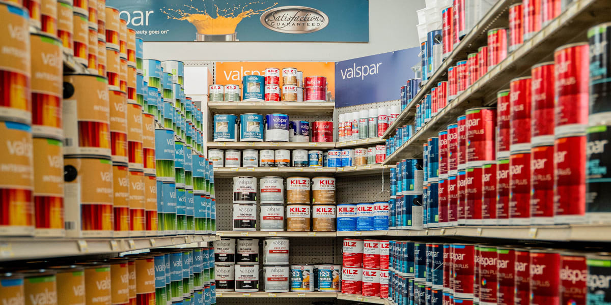 Interior view of a well-organized paint aisle showing extensive shelving stocked with paint cans from floor to ceiling