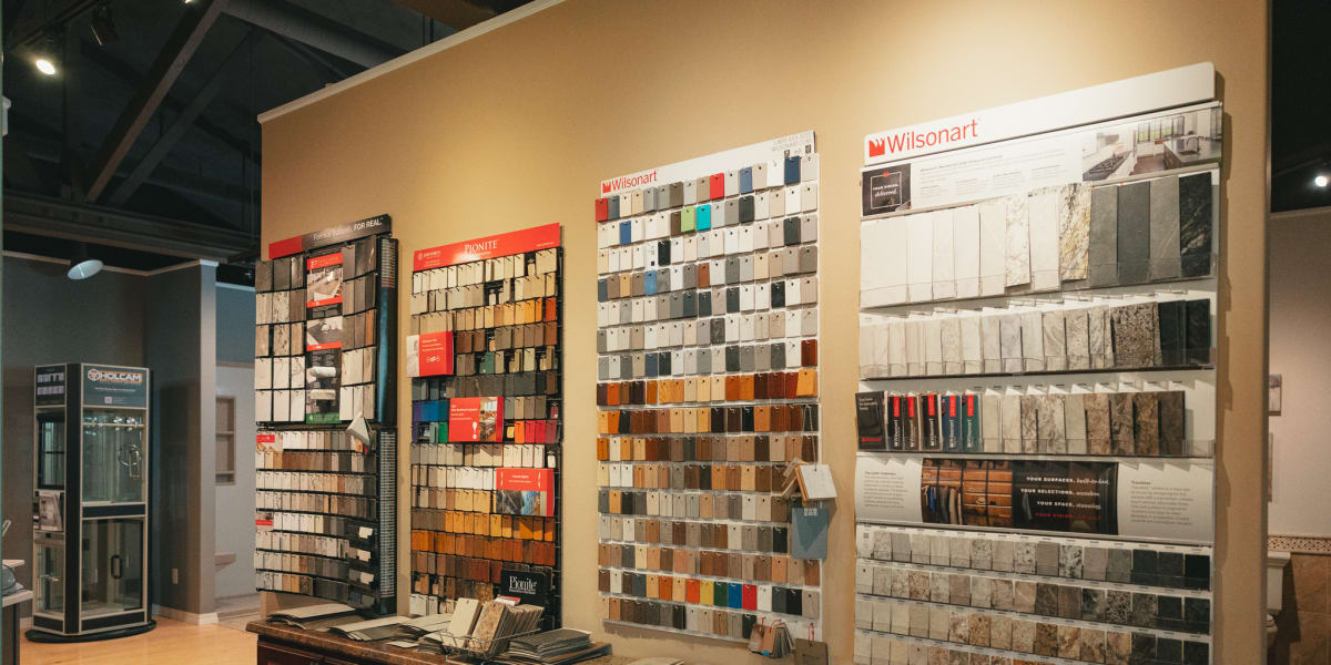 Interior view of a paint and surface materials showroom featuring extensive wall displays of paint color samples, laminate sa