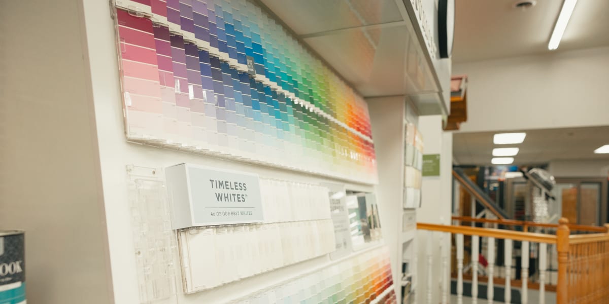 Interior view of a paint department showing extensive color sample displays arranged in rainbow patterns along the wall