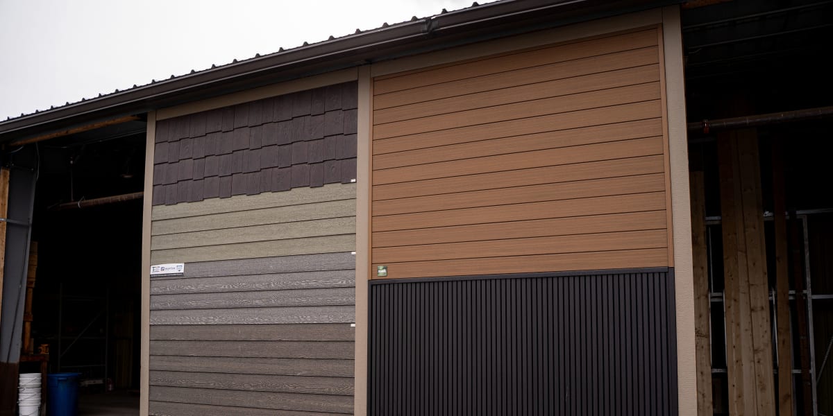 This image shows a display wall featuring various siding material samples and options