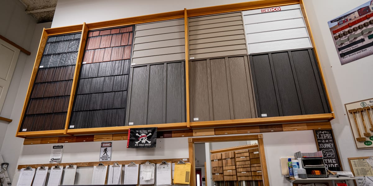 A large wall-mounted display showcasing various siding and exterior material samples in a showroom setting