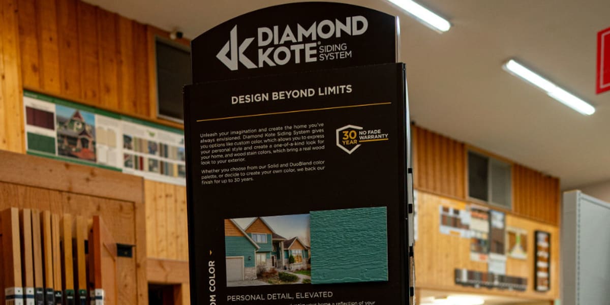 A tall black Diamond Kote siding system display stand in a store interior, featuring multiple color samples organized in rows