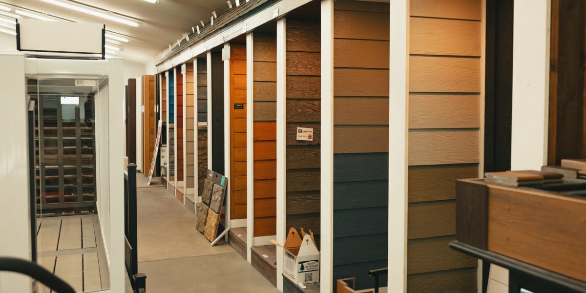 Interior showroom display featuring multiple vertical panels of different siding materials and colors arranged on white displ