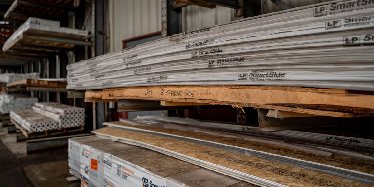 Stacks of LP SmartSide engineered wood siding panels stored in an industrial warehouse setting