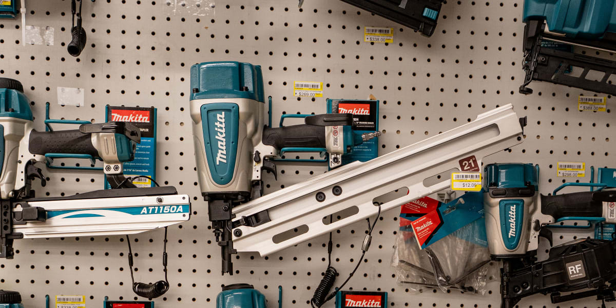 A pegboard display wall showcasing multiple Makita nail guns and brad nailers in the characteristic teal and white color sche