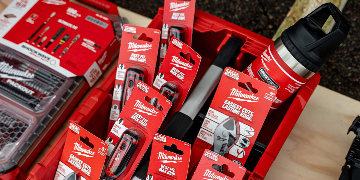 A red Milwaukee Packout tool storage crate filled with various Milwaukee hand tools and accessories in their original red pac