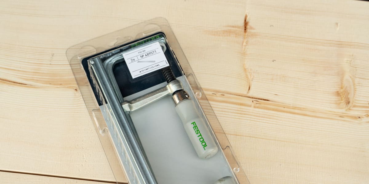 A Festool pneumatic nail gun displayed in clear plastic packaging on a light wood surface