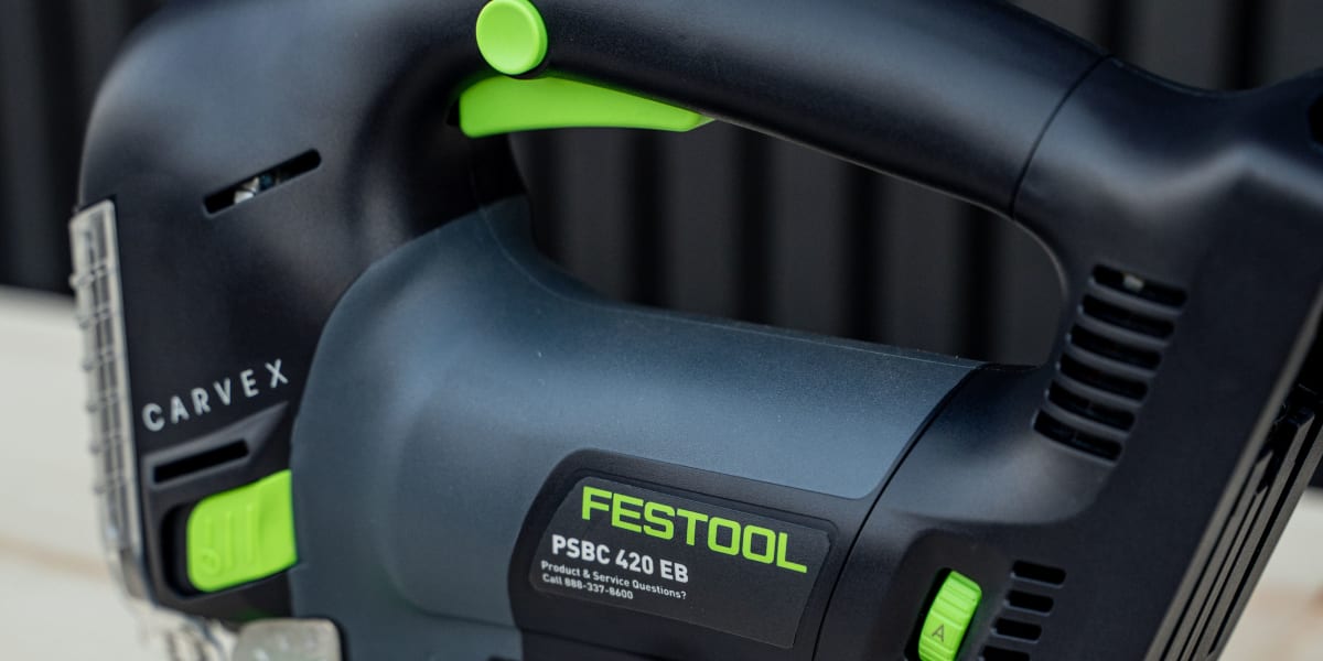 A Festool PSBC 420 EB jigsaw power tool is positioned on a wooden surface, featuring the characteristic dark blue and bright