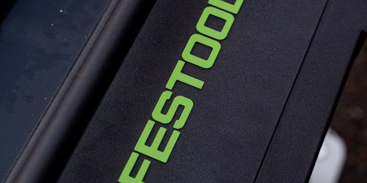 Close-up detail shot of a black Festool power tool or case with the distinctive green Festool logo prominently displayed on t