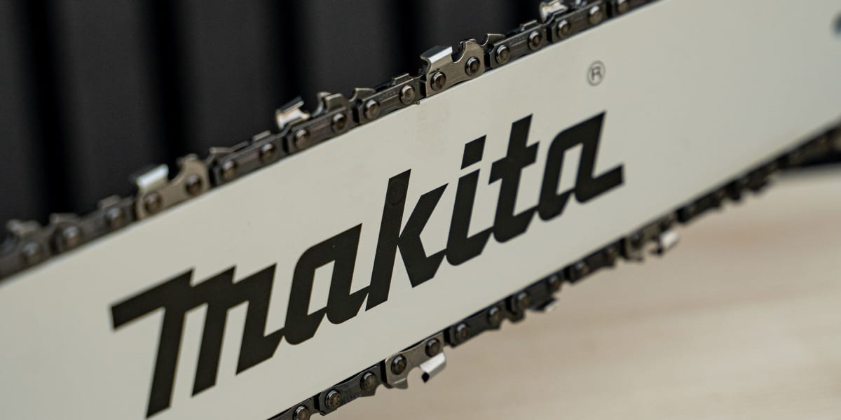 Close-up detail shot of a Makita chainsaw guide bar showing the brand logo prominently displayed on the white metal bar
