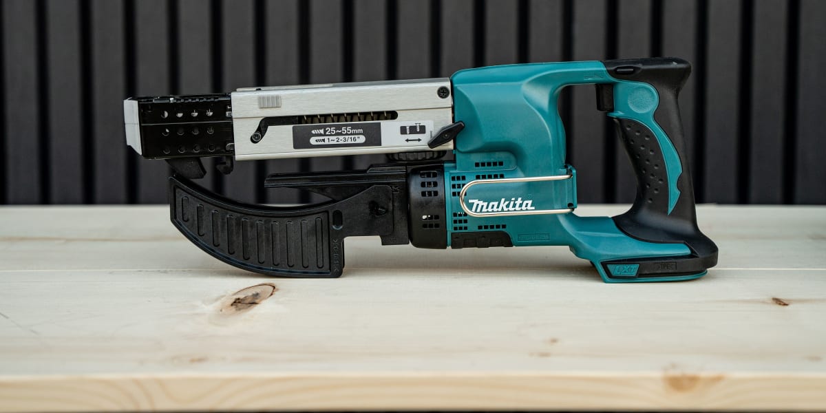 A Makita cordless strip nailer power tool displayed on a light wooden surface against a black slatted background