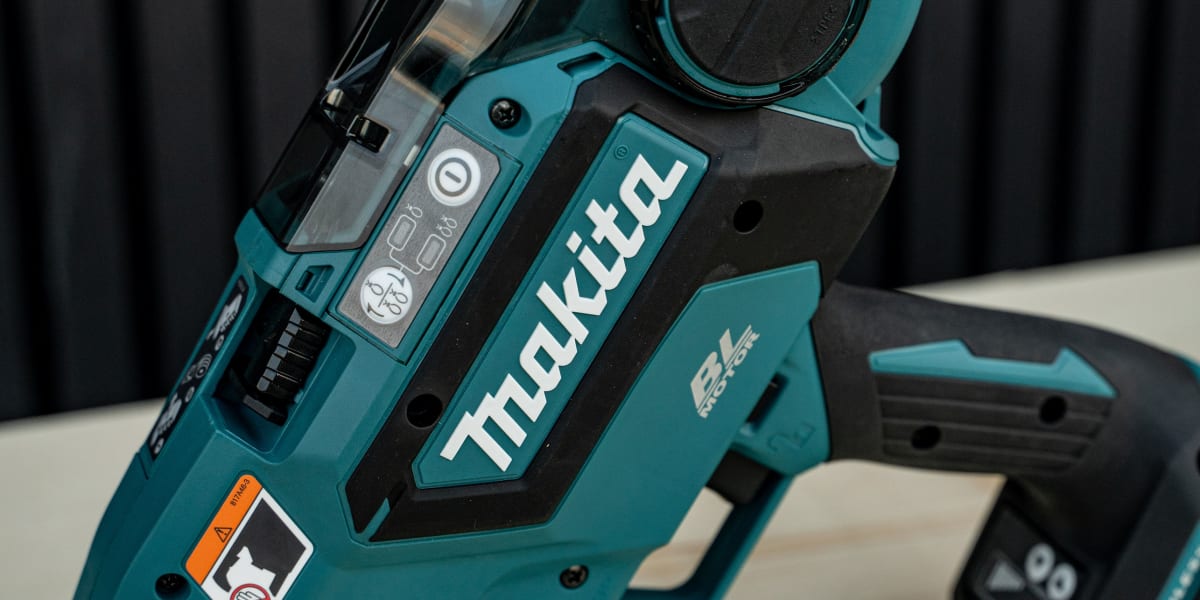 A teal-colored Makita cordless power tool, appears to be a compact circular saw or cutting tool, photographed on a light wood