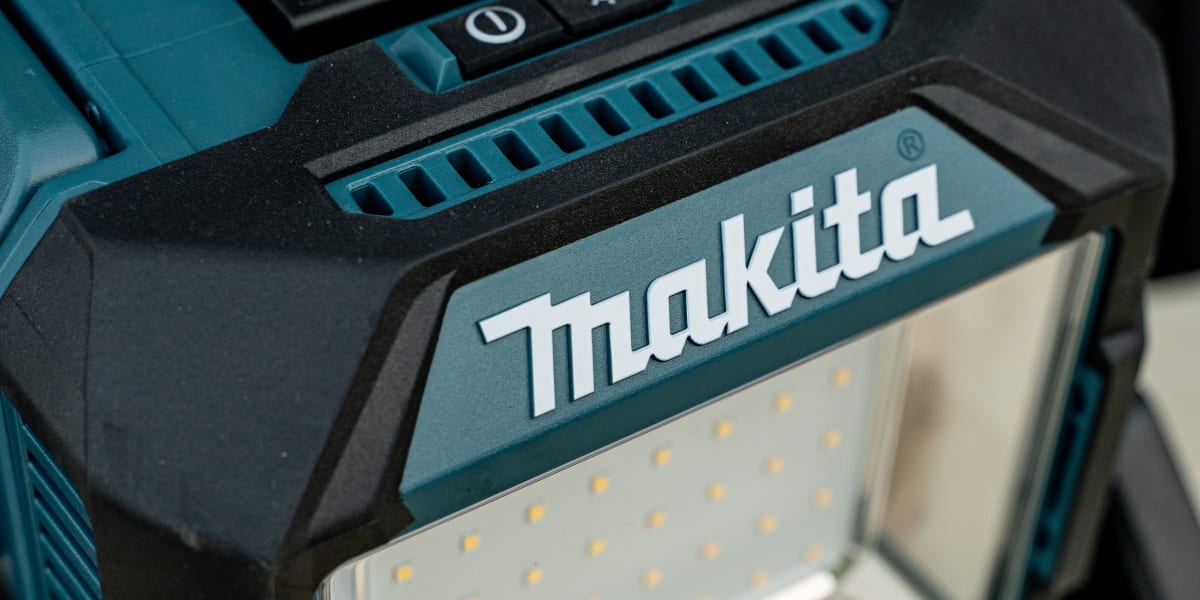 Close-up detail shot of a Makita cordless work light showing the LED panel illuminated with bright white light