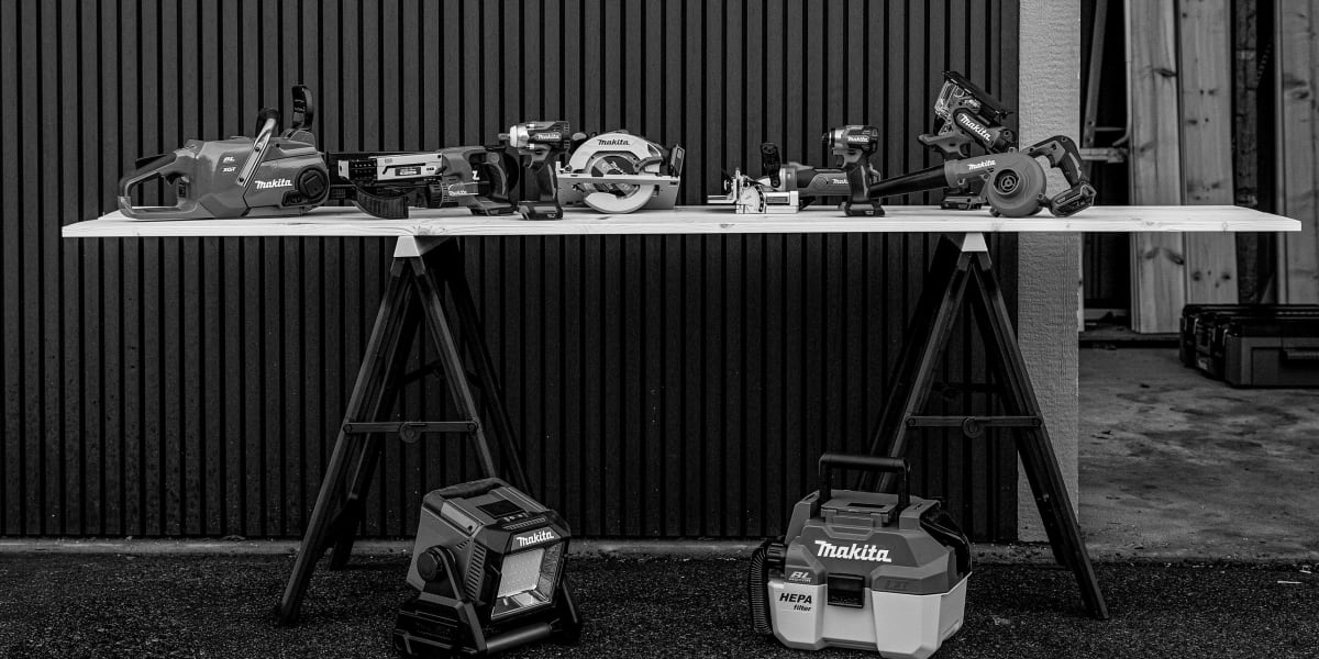 A black and white photograph showing a professional tool display setup with various power tools arranged on a white table sup