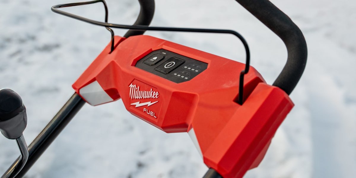 A Milwaukee FUEL cordless power tool, likely a blower or outdoor power equipment, positioned on snow-covered ground with a wi
