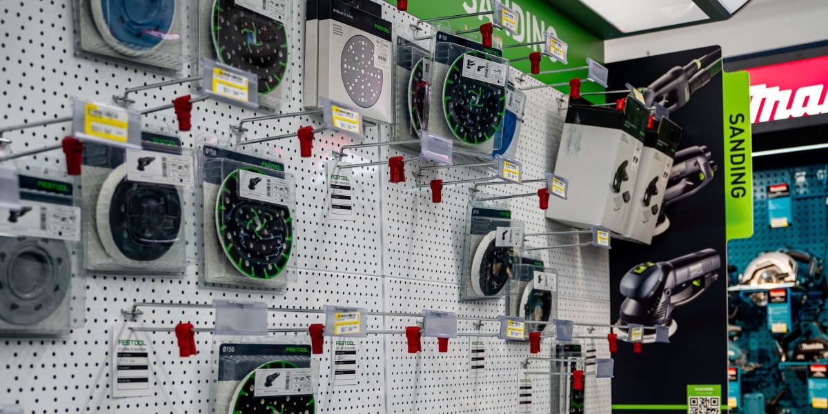 A retail display showing Festool sanding equipment and accessories on white pegboard walls