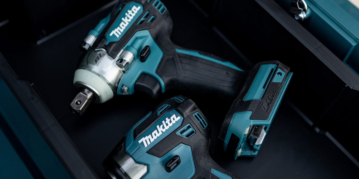A teal Makita tool case opened to display two cordless power tools and batteries stored in custom foam inserts