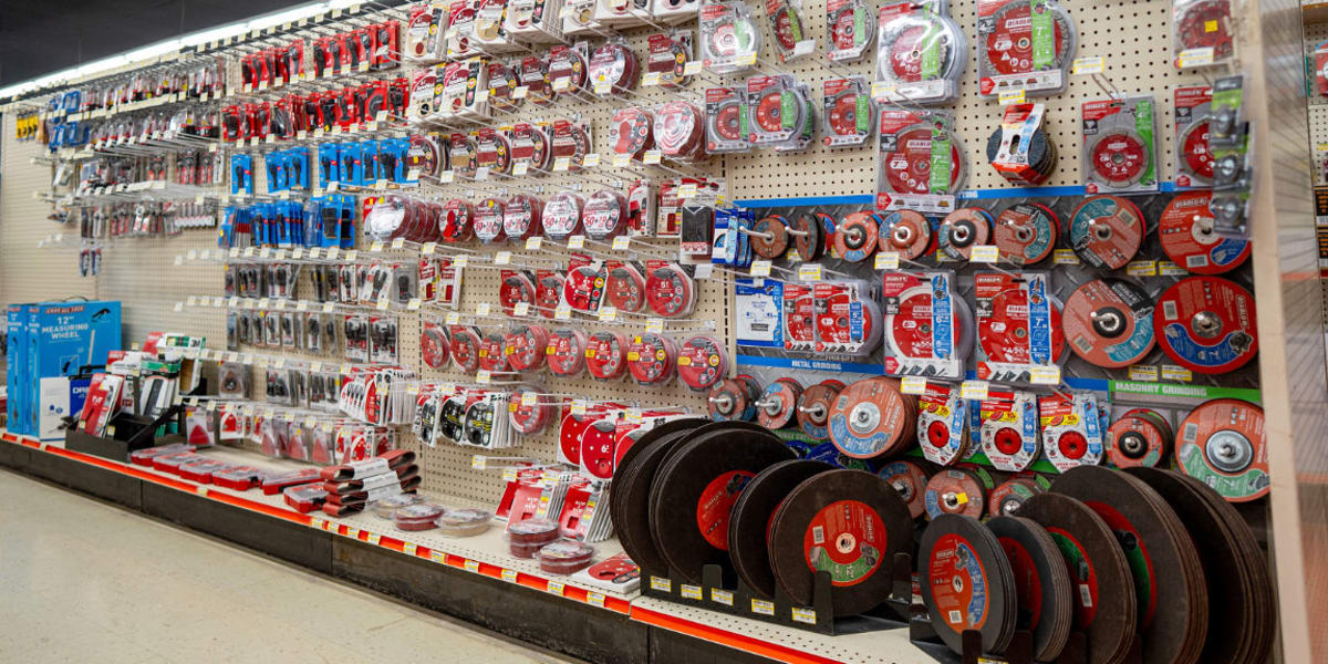 This image shows an extensive tools aisle in a building supply store featuring a large pegboard wall display of cutting wheel