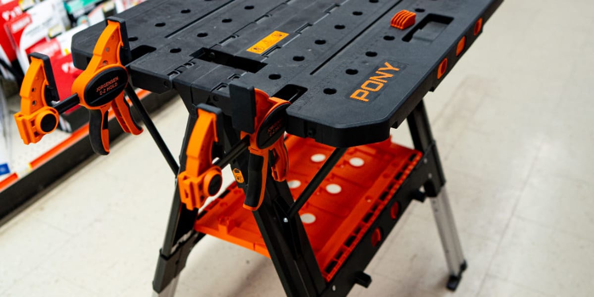 A FOMY brand portable folding workbench is displayed prominently in a store aisle