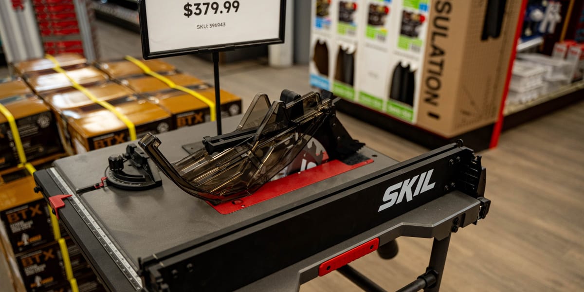 A SKIL branded portable workbench/table saw station displayed in a retail store environment
