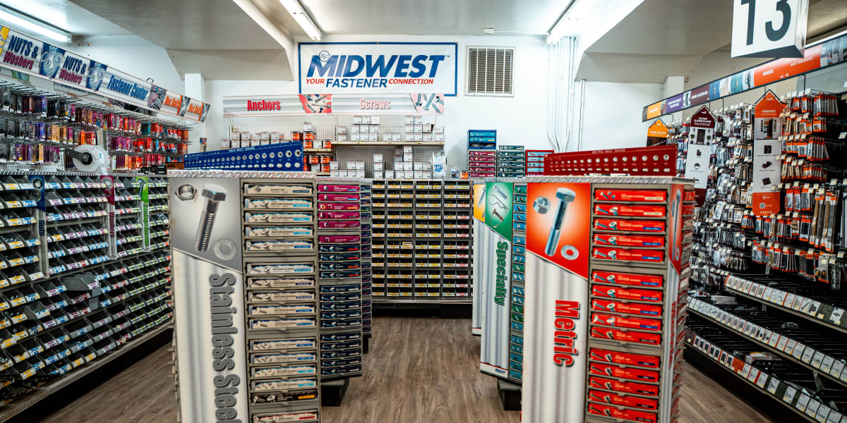 Interior view of a hardware store's fastener aisle showing organized displays of nuts, bolts, screws, and washers in multiple