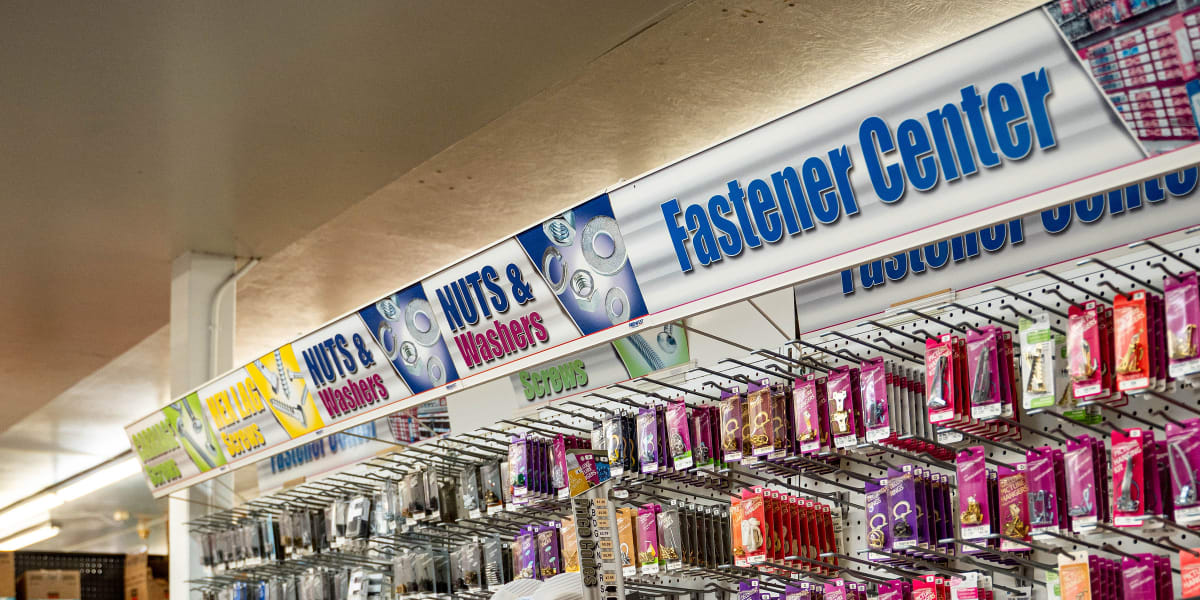 This image shows a well-organized hardware aisle featuring a fastener center with extensive shelving systems displaying screw